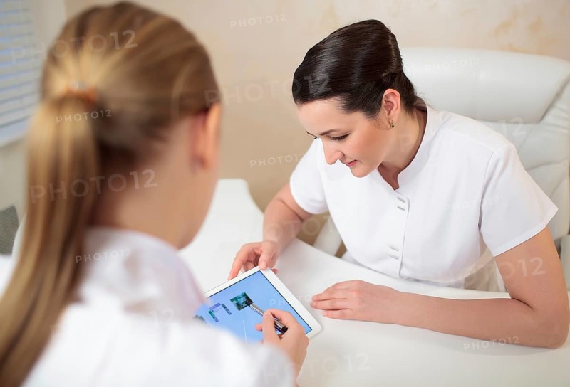 Two woman beauticians in the office room talking about job using tabet PC