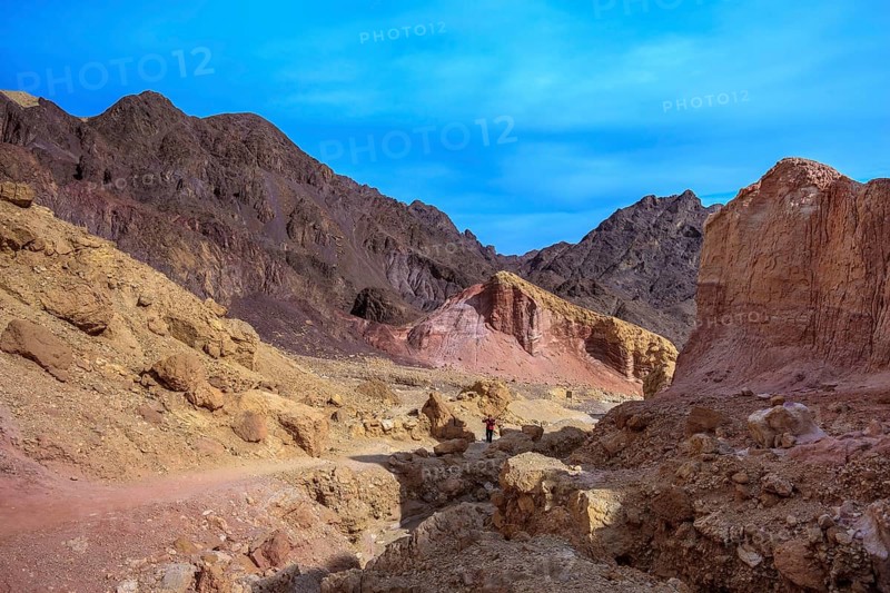 Dry stone desert near the southern seaside resort of Eilat. Woman photographer on a dirt road at the foot of King Solomon