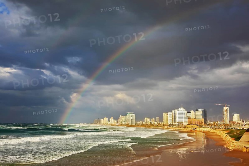 Storm cloud hanging over the sea, gorgeous huge rainbow crossed the sky. Promenade and beach in Tel Aviv