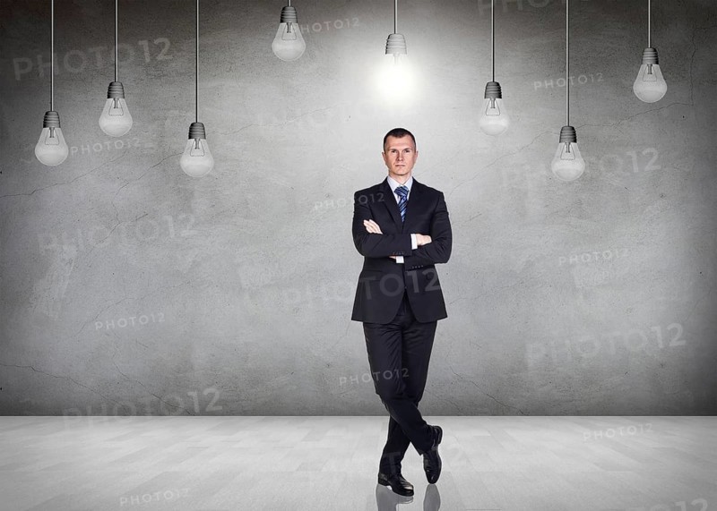 Businessman stands in a gray room with hanging bulbs