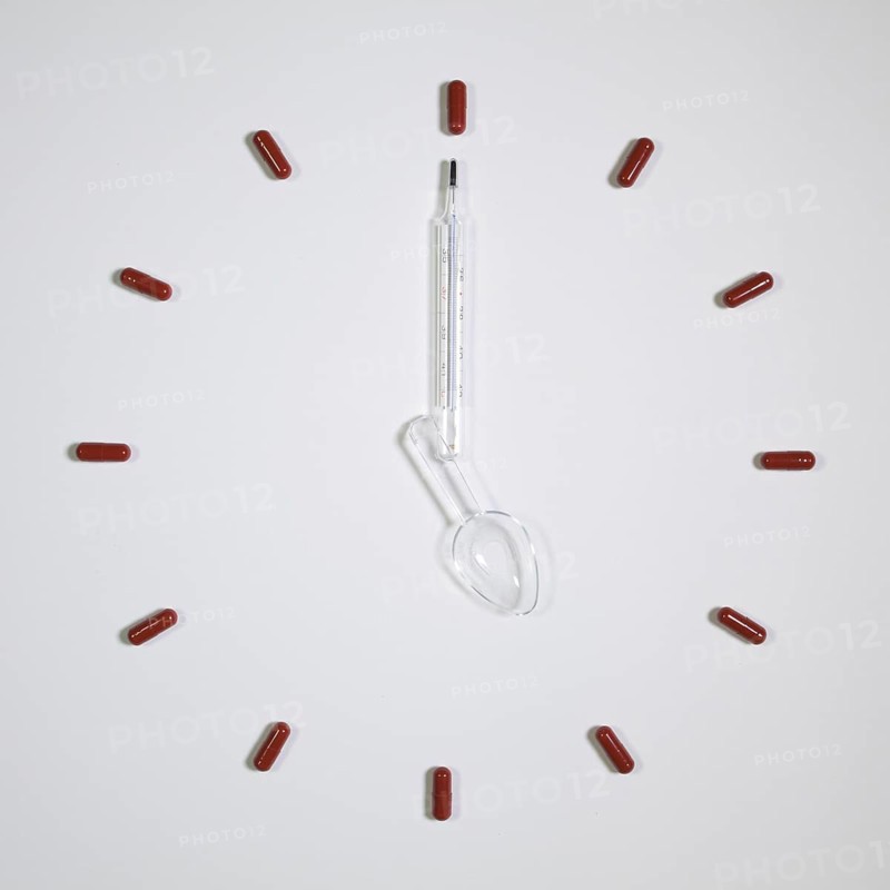 Time - Clock of twelve pills, medical thermometer and plastic spoon