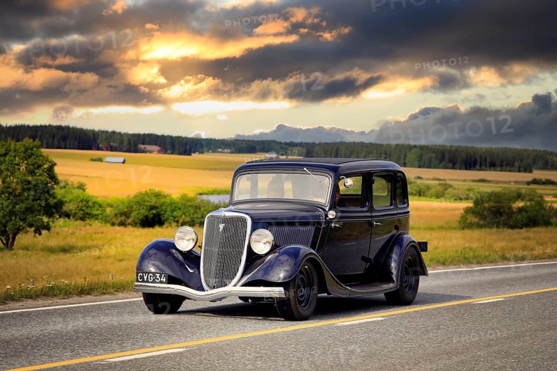 Black Ford Fordor Dillinger Special year 1934 on road on Maisemaruise 2019 car cruise. Edited sky. Vaulammi, Finland. August 3, 2019