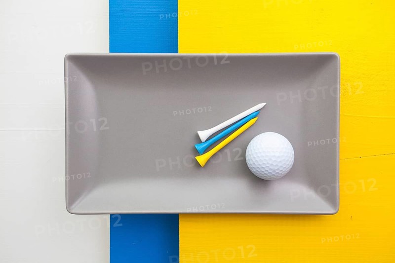 Gray ceramic dish with golf equipments on over white, blue and yellow wooden table, rectangle dish