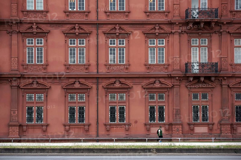 Mainz, Germany - June 24, 2015: A tourist wearing a green waistcoat and hiking clothes walks along the east facade of the Electoral Palace Mainz on 24 June 2015 in Mainz, Germany