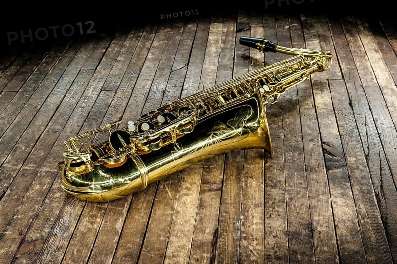 Beautiful golden saxophone lies on a wooden floor