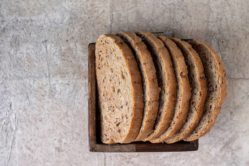 Slices of whole grain bread lie in a square wooden box, copy space, selective focus