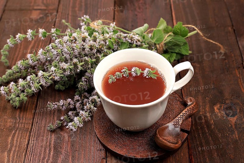 Flower tea with mint on an old wooden table, has a calming and relaxing effect, alternative medicine concept