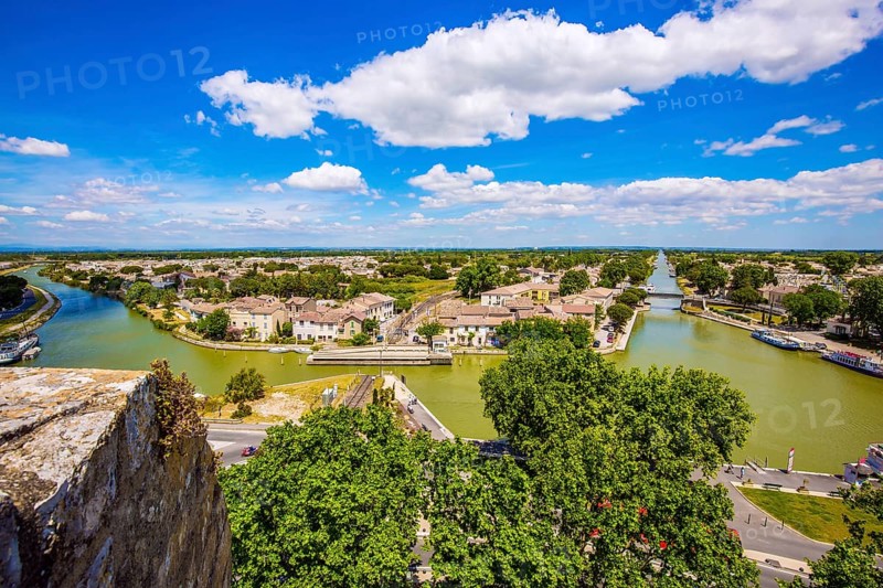 Shipping channel flows into the Mediterranean Sea. Antique walls of the medieval port city of Aigues-Mortes. Yachts moored off the coast. France. The concept of historical and photo tourism