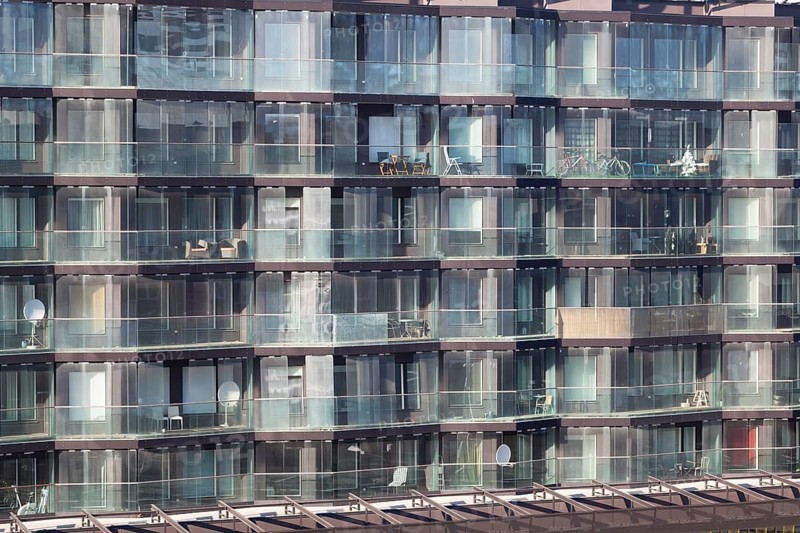 Architectural background of the exterior of a modern apartment block with large glass windows and balconies in an example of high density living