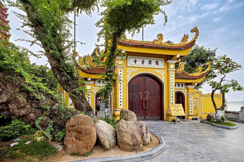 Magnificent Tor tor with golden decorations and trees leading into a Buddhist temple complex, The Tran Quoc Pagoda at Westlake in Hanoi Vietnam