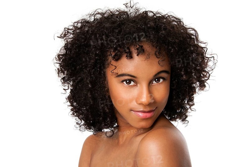 Beautiful happy female face with smooth skin and dark curly hair, isolated, New York, USA
