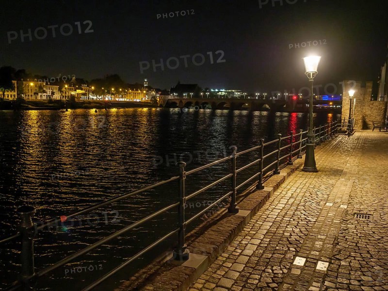 River course at night, illuminated by lights and reflecting water surface, maastricht, the netherlands