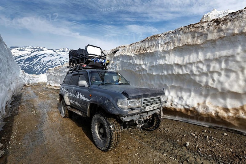 KAMCHATKA PENINSULA, RUSSIA, JUNE 18, 2017: Japanese extreme off-road expedition car Toyota Land Cruiser driving on mountain road in snow tunnel surrounded by high snowdrifts on Vilyuchinsky Pass