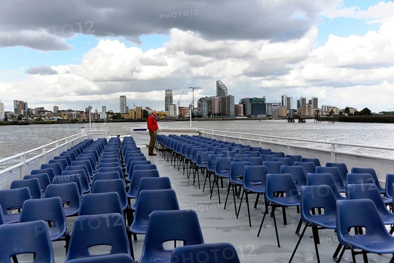 River cruise with empty chairs on the deck, modern city view in the background, London, London region, England, United Kingdom
