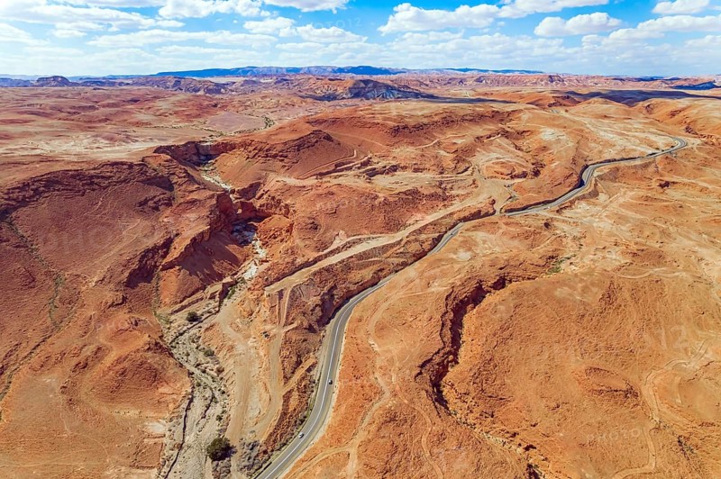 Judean desert on the shores of the Dead Sea. Dry waterless hills of yelloy and beige clay. Magnificent road are laid among the hills. Shooting from a drone, from a bird's eye view. Israel