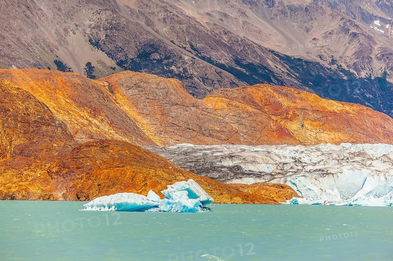 Massive glacier descends into the emerald water. In the water ice-floes, broken away from a glacier. The picturesque multi-colored shore of Lake Viedma