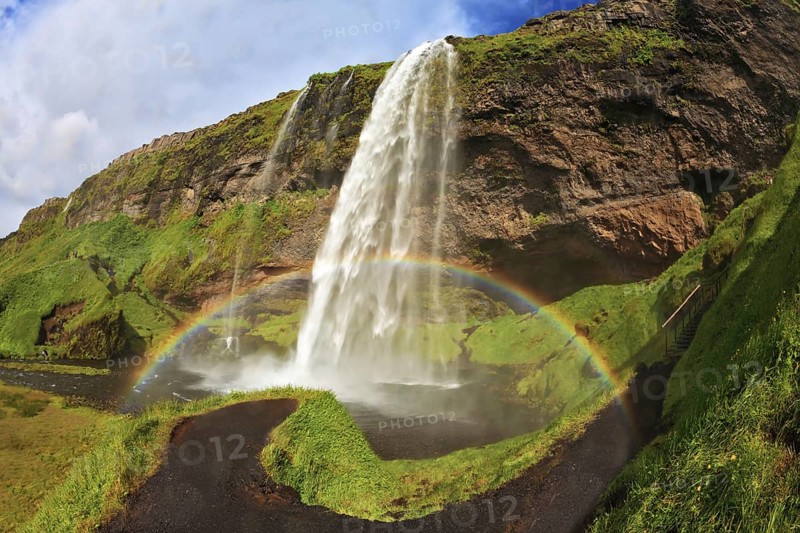 Summer sunny day. Large rainbow decorates a drop of water. Seljalandsfoss waterfall in Iceland. The picture was taken Fisheye lens