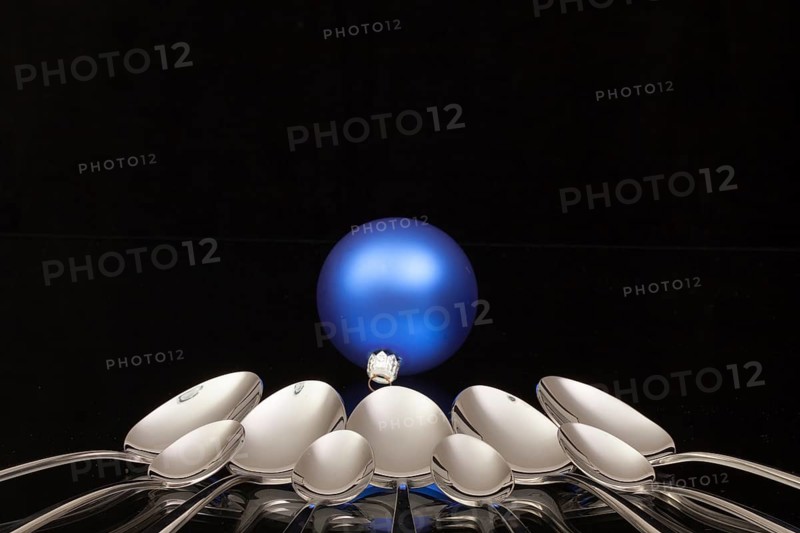 Blue Christmas decoration and nine spoons on a black glass desk