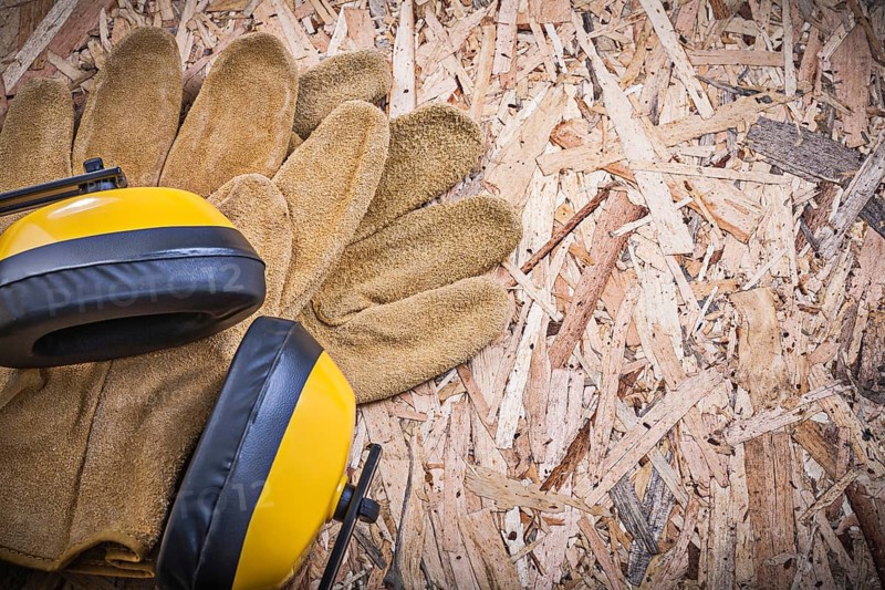 Safety leather gloves earmuffs on chipboard