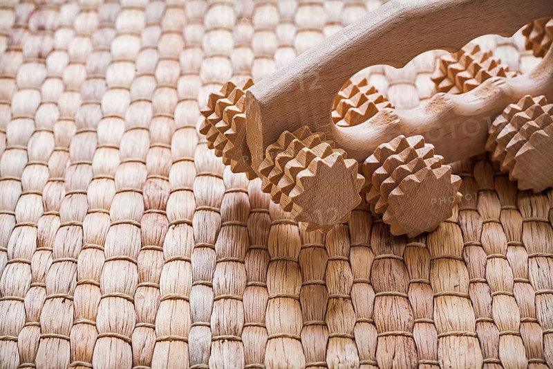 Wooden relaxing massager on wicker background sauna concept