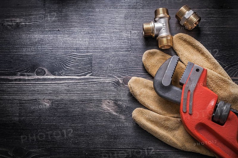 Monkey wrench brass plumbing fittings leather safety gloves construction concept
