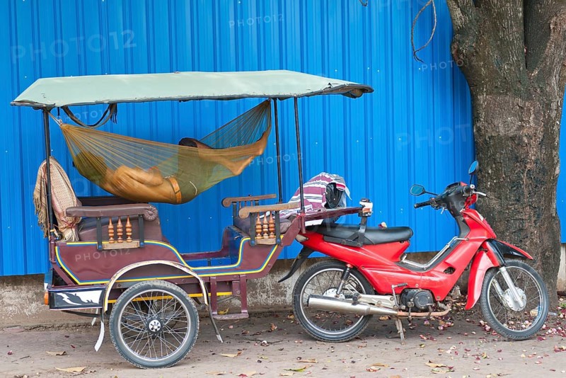 A Cambodian driver sleeps in hammock in his tuktuk