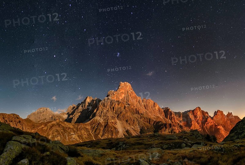 Cimon delle Pala mountain above Passo Rolle with clouds at night with stars