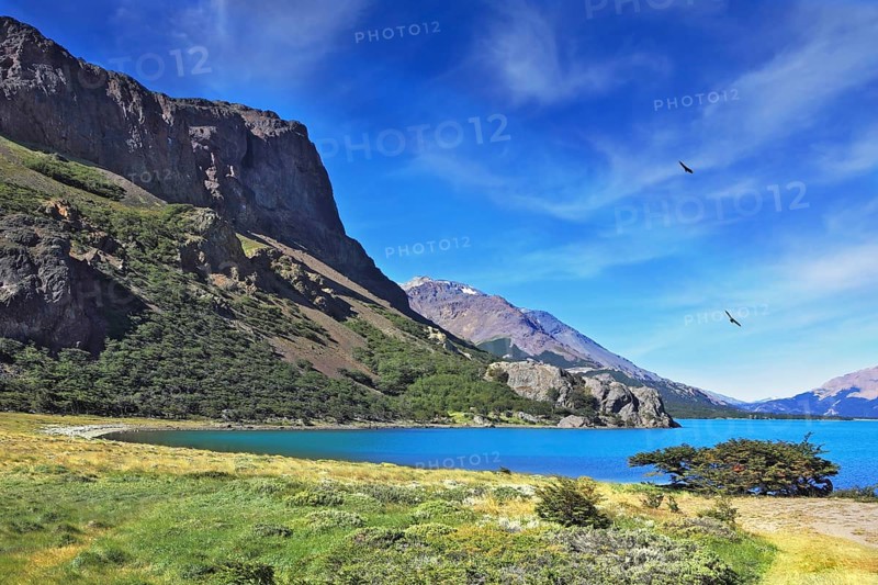 Mountain lake with blue water. Above the lake Andean condors flying in circles
