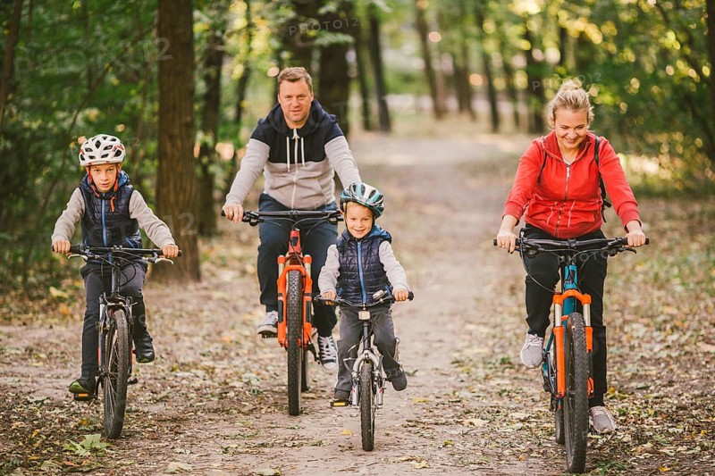 Parents and kids cycling on forest trail. family in warm clothes cycling autumn park. Family mountain bike on forest. active sports outdoor recreation. portrait Family Cycling Through Fall Woodland