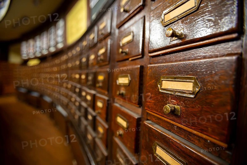 Wooden drawers with metal ornaments in an old-fashioned library. Wooden boxes with index cards in library