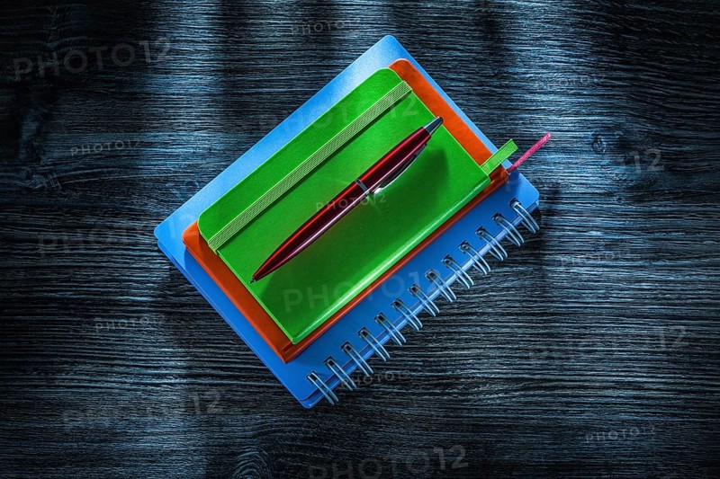 Pile of notebooks pen on vintage wooden board