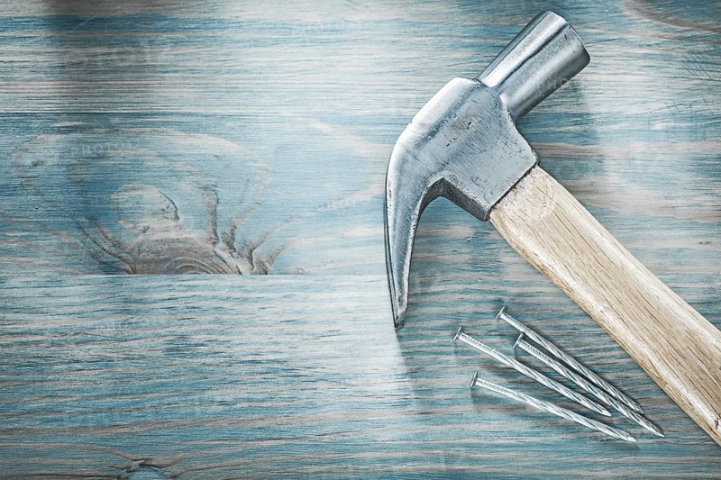 Claw hammer metal nails on wooden board top view construction concept