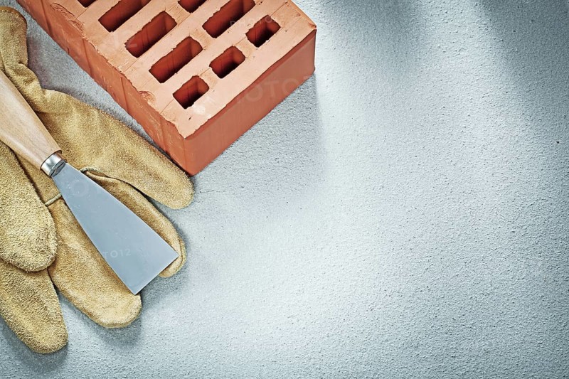 Building bricks leather safety gloves paint scraper on concrete background bricklaying concept