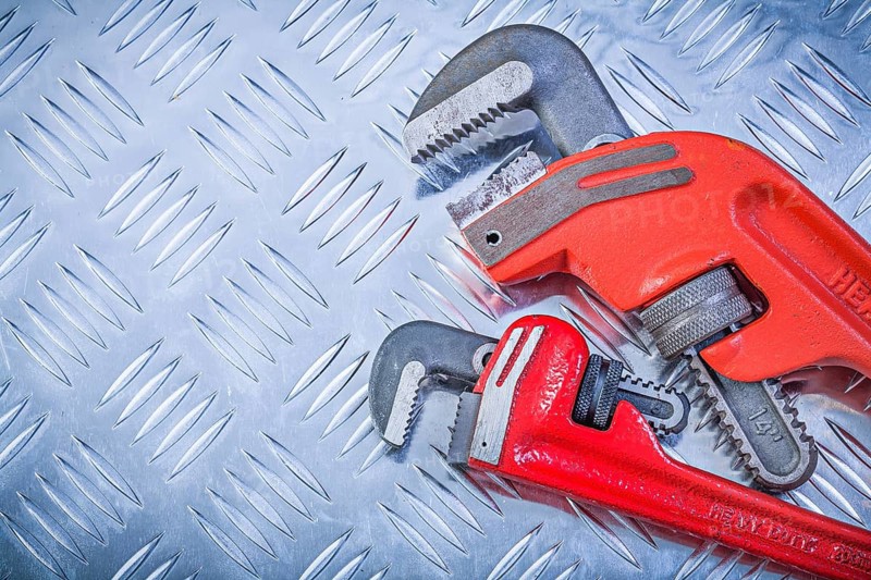 Set of pipe wrenches on fluted metal plate construction concept