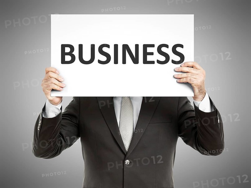A business man holding a paper in front of his face with the word business