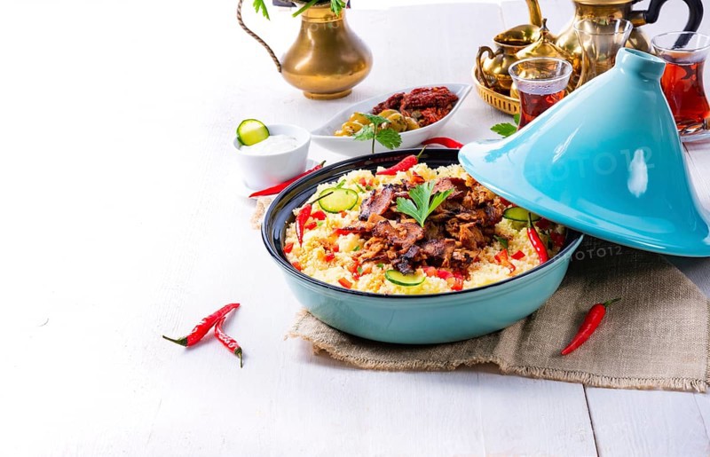Tajin with couscous, vegetables and meat on a white background