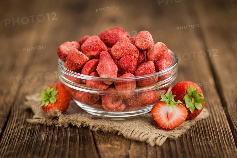 Strawberries (dried) as high detailed close-up shot on a vintage wooden table, selective focus