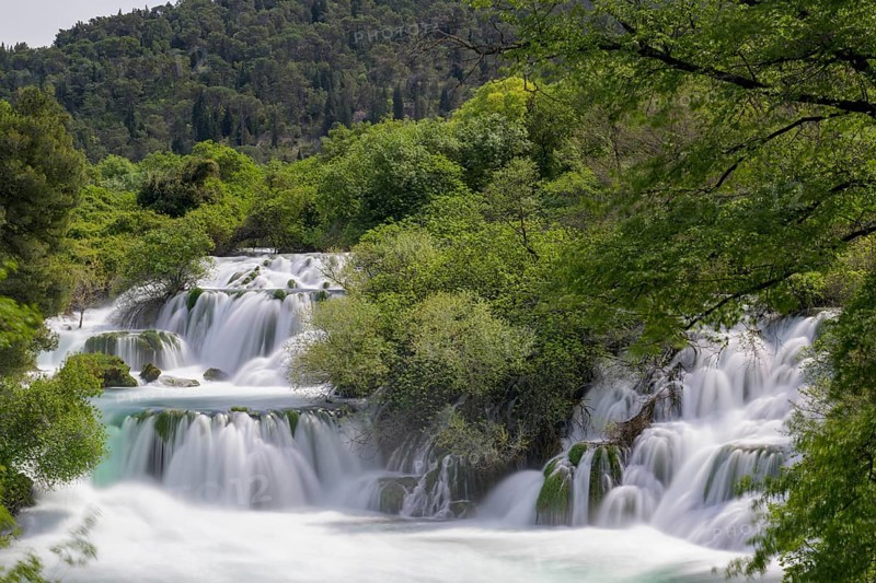 Several waterfalls flow through a lushly wooded hilly landscape, Krka Krka Waterfalls National Park, Croatia