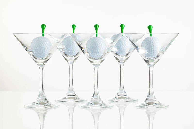 Five glasses of champagne and golf equipments on the glass desk