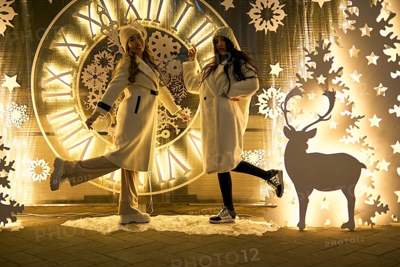 Two girlfriends asian girls in white coats are having fun hugging, new year, light bulbs