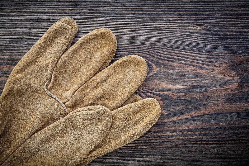 Pair of leather protective gloves on vintage wooden board agriculture concept