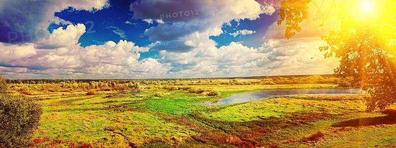 Panoramic view on big meadow with small flood sky with sun instagram stile