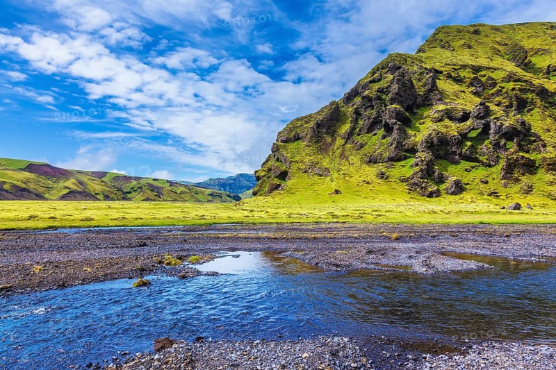 Pakgil Canyon - green grass and moss on the rocks. At the bottom of canyon flows small fast creek. Summer blooming Iceland