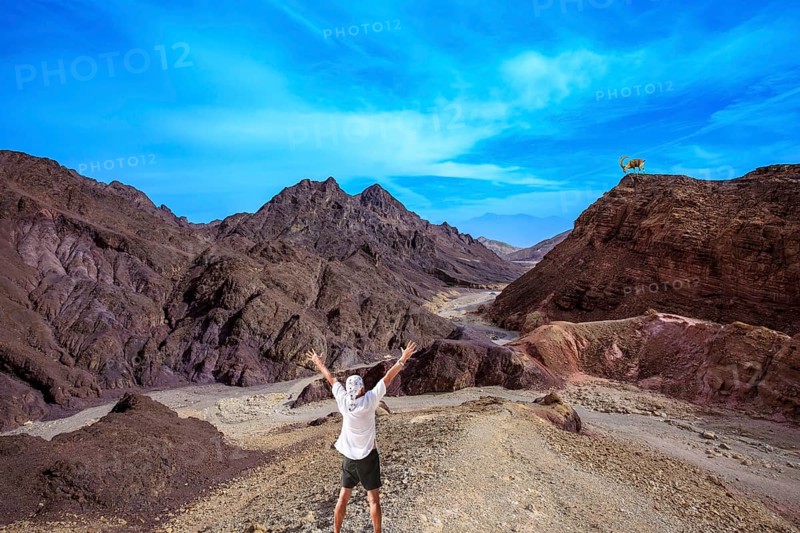 Lone tourist threw his hands up in delight in Eilat Mountains. Unique outcrops in the mountains of pink sandstone
