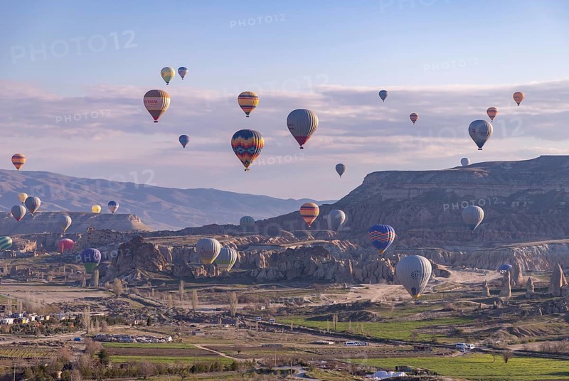 A picture of colorful hot air balloons flying over the landscape of Goreme Historical National Park at sunrise