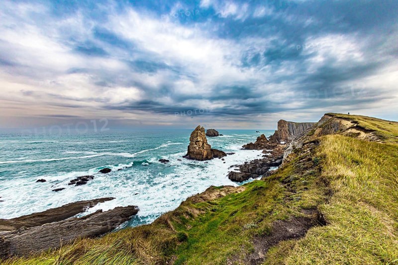 Portio beach. Rocky coastline of the Atlantic Ocean. Spanish coast, Cantabria. Stormy autumn day in the Bay of Biscay. Picturesque cliffs and huge stones oppose the ocean