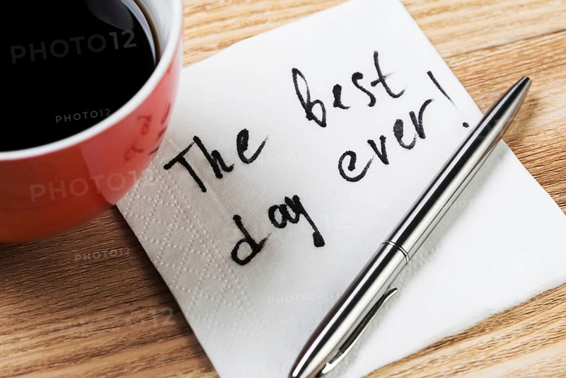 Coffee cup pen and napkin with words on wooden table