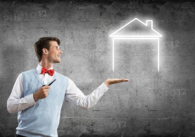 Confident and young businessman smoking pipe and drawn house on gray wall background