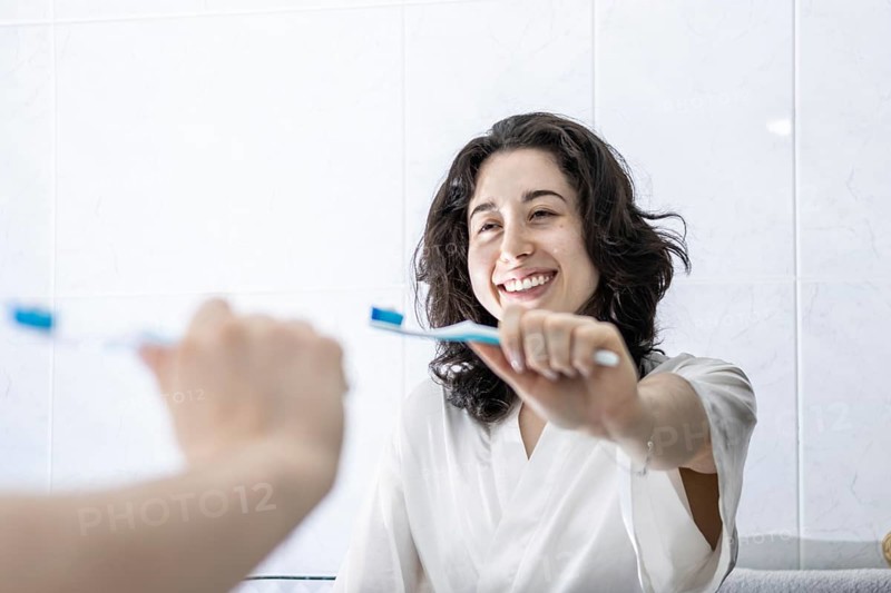 Portrait of a pretty young latin girl holding a toothbrush and smiling in front of the mirror. having proper oral hygiene makes you feel happier