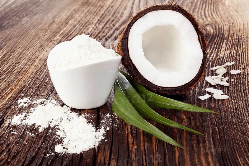 Fresh coconut half on wooden table with coconut flour. Healthy flour eating